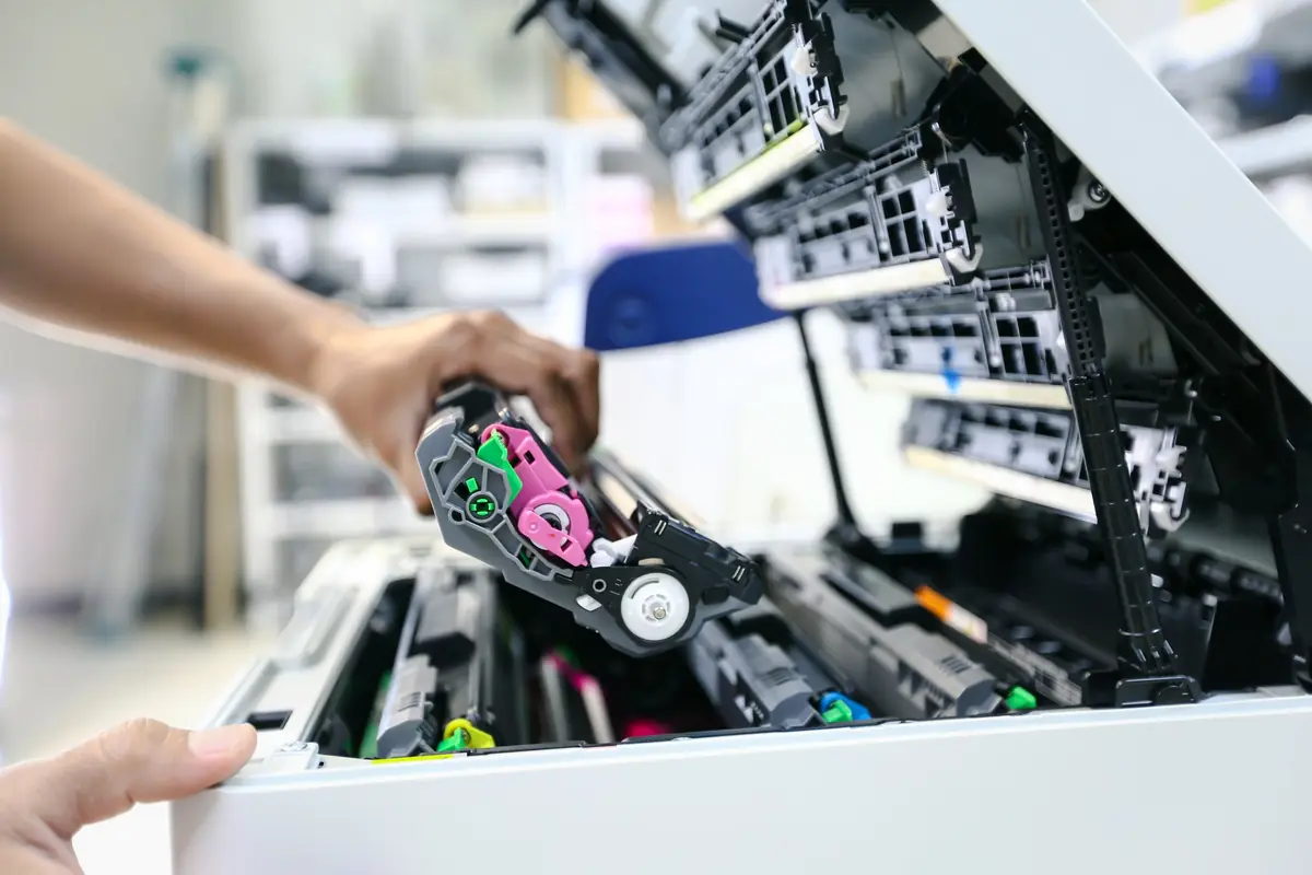 Hand removing a color toner cartridge from an open laser printer