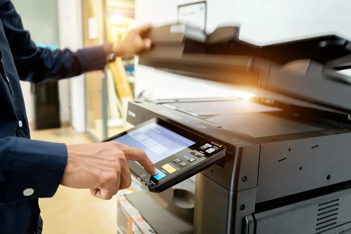 Office worker pressing the start button on a multifunction copier's touchscreen panel