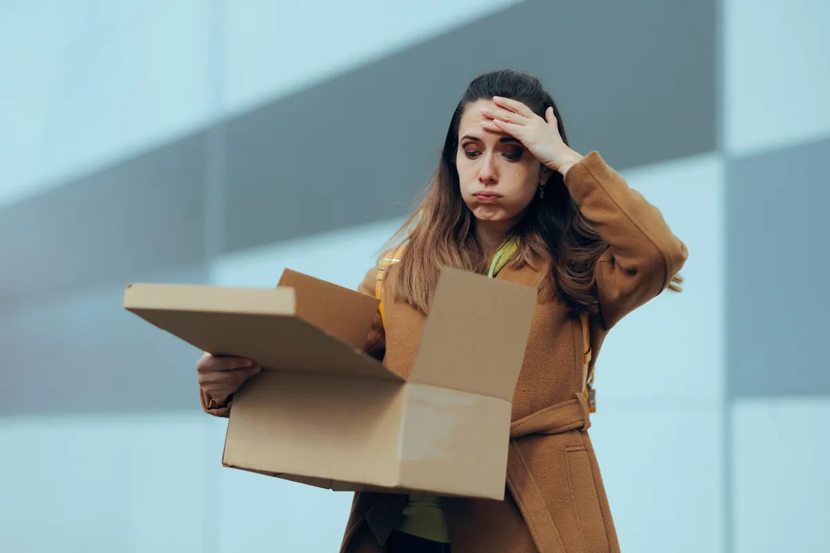Frustrated woman holding her forehead while looking into an open cardboard box