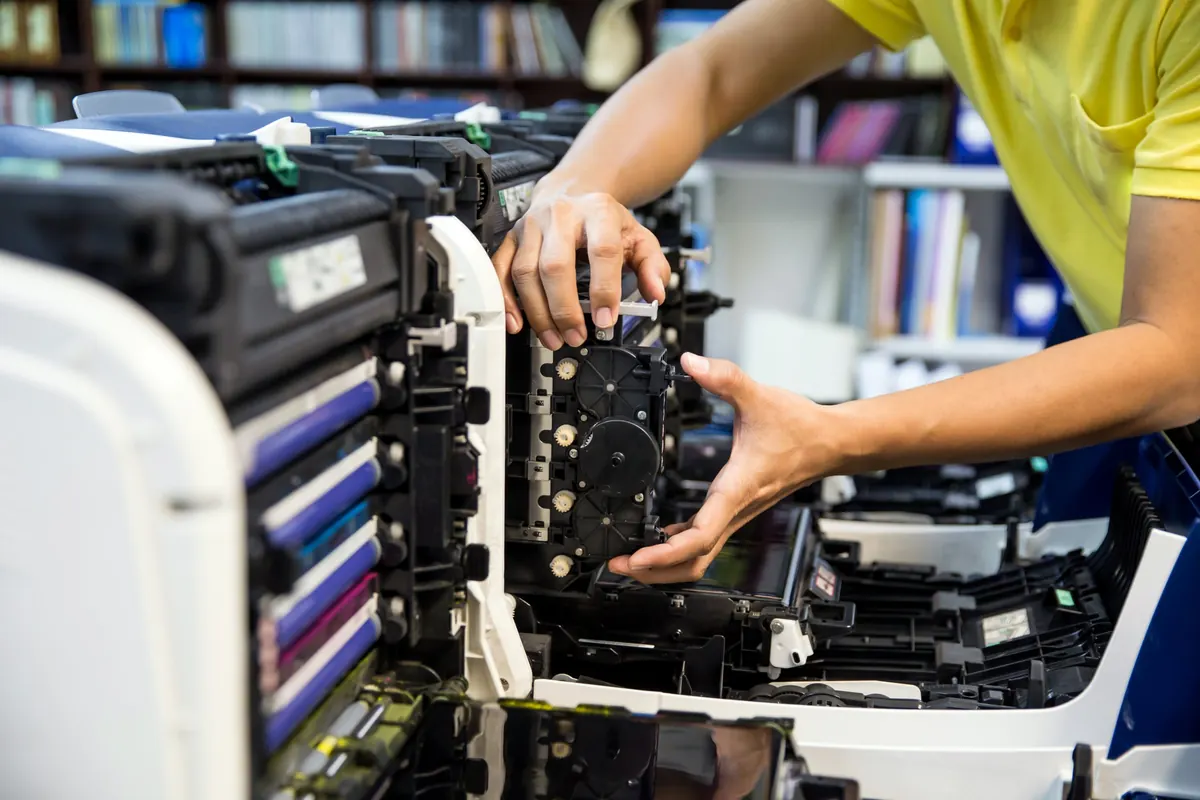 Technician removing a drive assembly from an open color multifunction copier